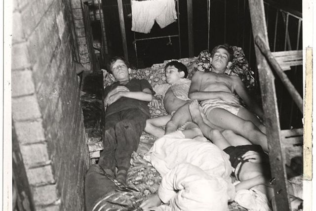 View of members of a family as they sleep outside on the fire escape of their tenement building, July 27, 1940.